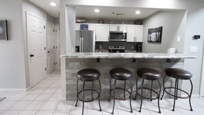A kitchen with a marble countertop, four stools, a microwave, a stove, and a refrigerator. - Parkview Bay, 3 bed, 3 bath, lakeview, elevator, wifi, pool (Osage Beach)