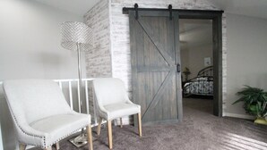 A room with two white upholstered chairs, a floor lamp, a wooden door, a bed with a metal frame, and a plant. - Parkview Bay, 3 bed, 3 bath, lakeview, elevator, wifi, pool (Osage Beach)