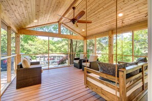 A wooden deck with wicker furniture and a ceiling fan.