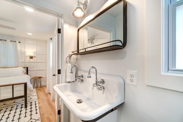 A modern bathroom with a white sink, two faucets, and a mirror.