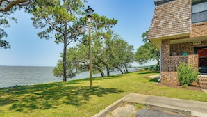 A residential property with a brick exterior, a lawn, and a view of the water. - Waterfront Nags Head Townhome w/ Amenity Access! (Nags Head)