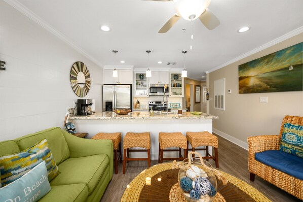 A modern kitchen with a central island, white cabinetry, and a ceiling fan.