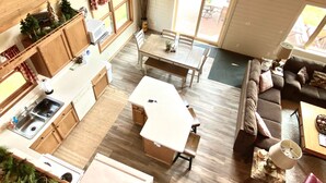 Amplia sala de estar con mesa de comedor, sofá y zona de cocina que incluye un fregadero y armarios.