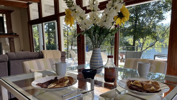 A dining table with breakfast plates, a vase with flowers, and a bottle of syrup. - Home on Hot Springs beautiful Lake Hamilton. TWO MASTER SUITES!!  (Hot Springs)