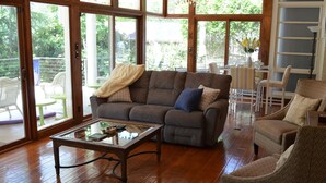 A living room with a brown sofa, a glass coffee table, and wicker chairs. - Home on Hot Springs beautiful Lake Hamilton. TWO MASTER SUITES!!  (Hot Springs)