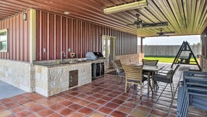 Eine Außenpatio mit einer Steintheke, einem Grill und einem Essbereich mit Stühlen und einem Tisch.