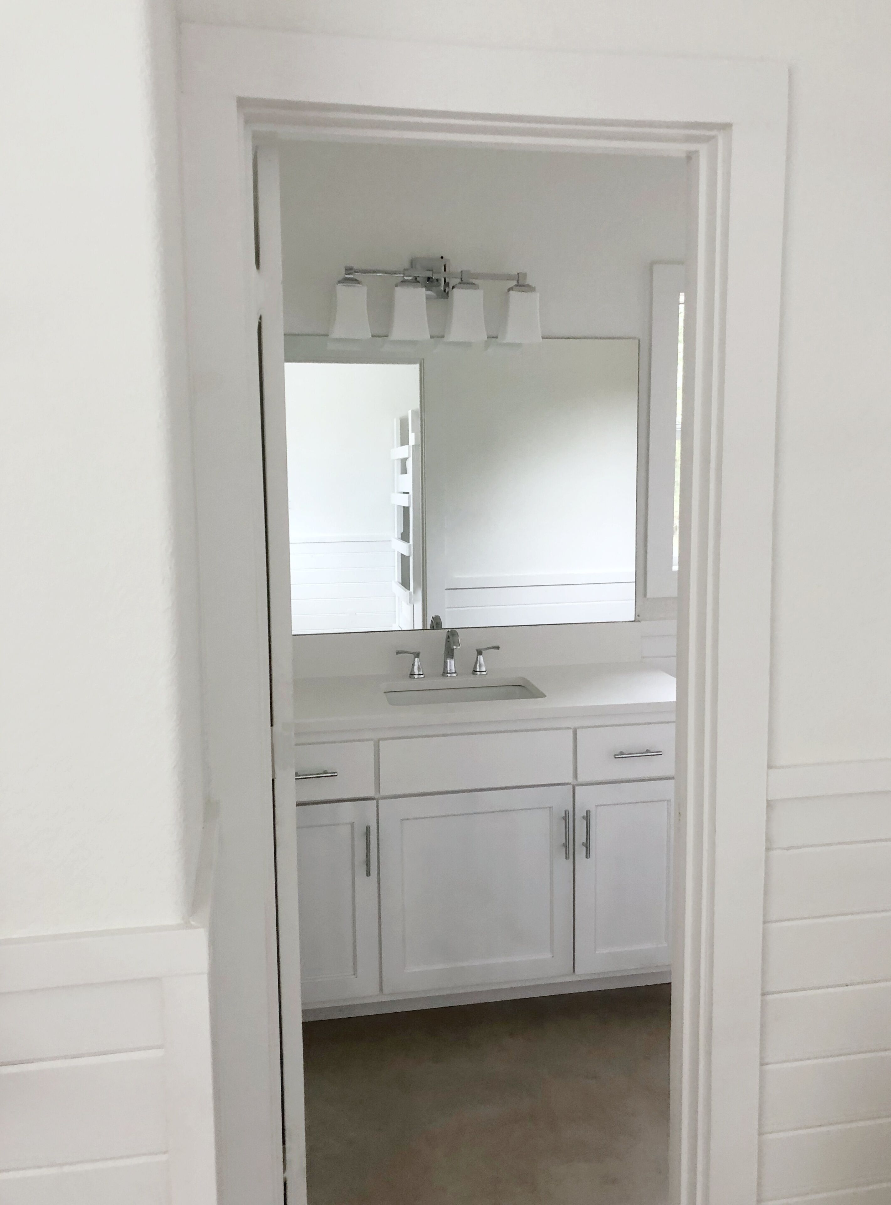 Une salle de bain avec un lavabo blanc, un miroir et des armoires.