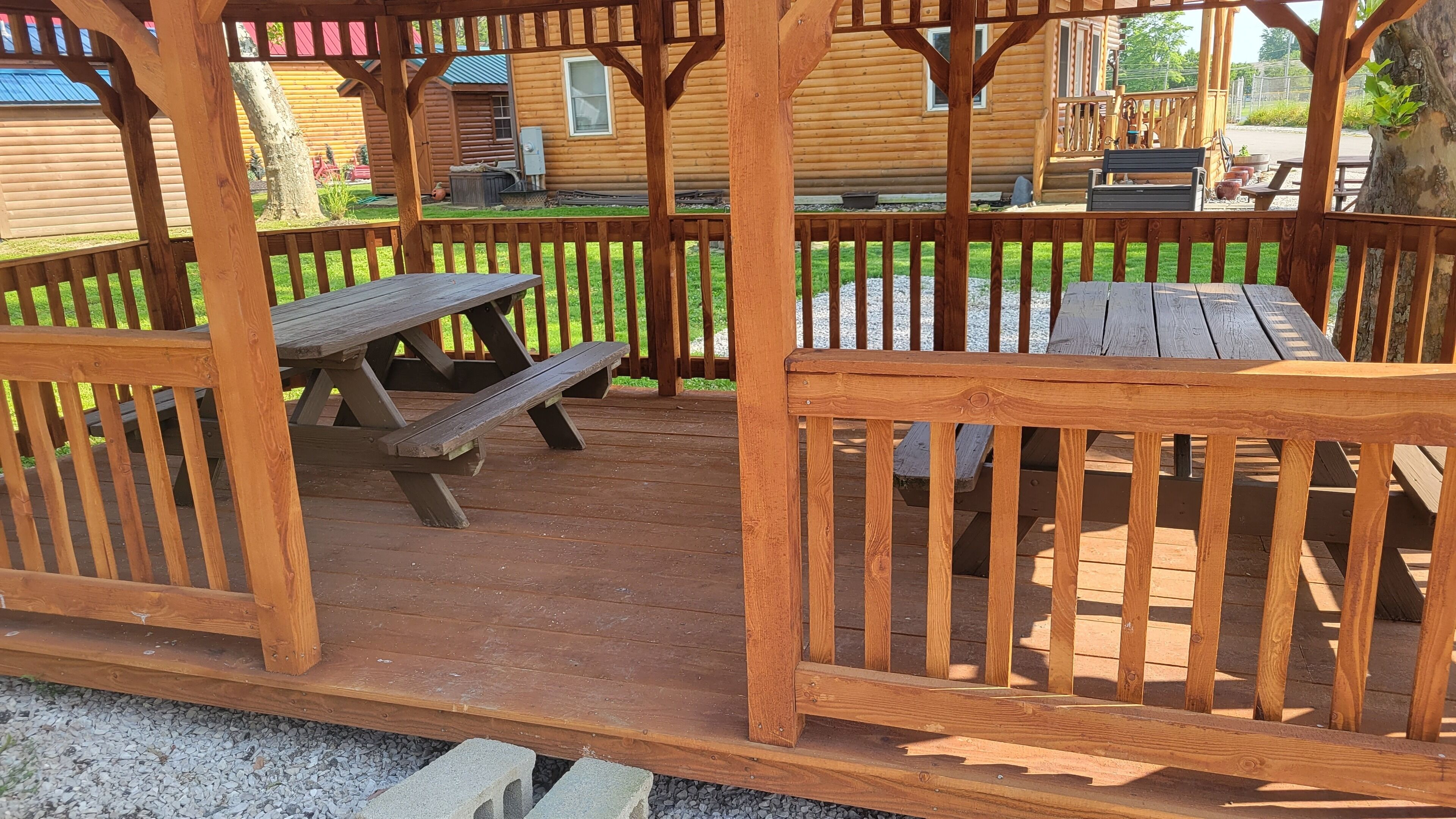 Un patio in legno con tavoli da picnic e una recinzione di legno.