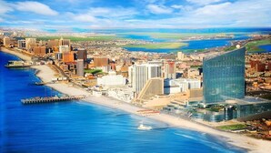 A coastal cityscape with a prominent modern glass building, a marina, and a beach.