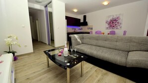Ein modernes Wohnzimmer mit einem grauen Sofa, einem Glastisch und einer weißen Orchideenpflanze.