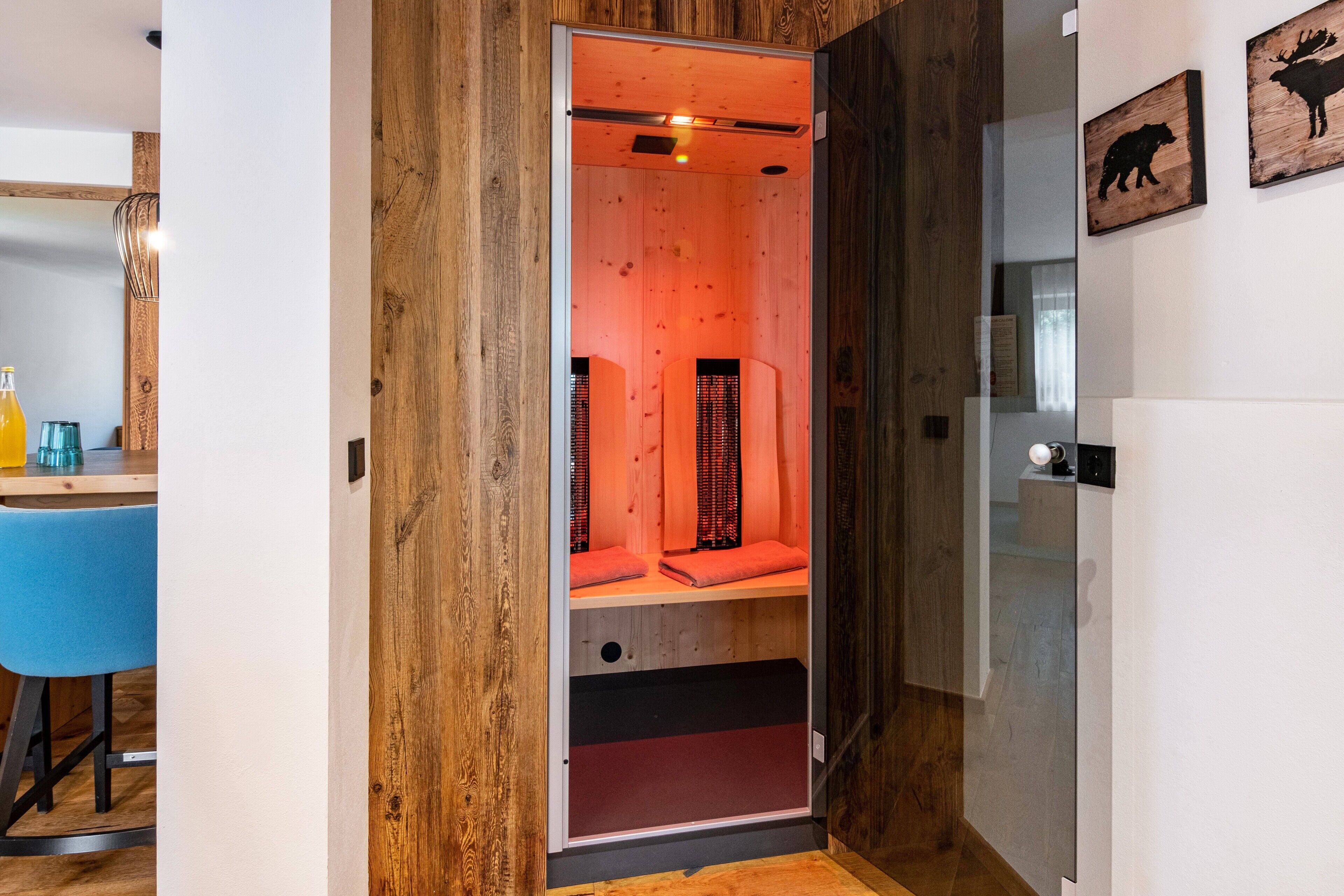 Un sauna avec un intérieur en bois, une porte en verre et un espace détente équipé de serviettes.