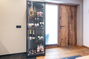 Une pièce dotée d’une porte coulissante, d’un meuble vitré contenant des bouteilles de vin et des en-cas, et d’un plancher en bois.