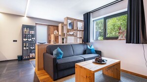 Un salon moderne avec un canapé gris, une table basse en bois et un meuble à bouteilles.