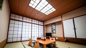 Una habitación tradicional japonesa con suelo de tatami, una mesa de madera baja y puertas correderas.