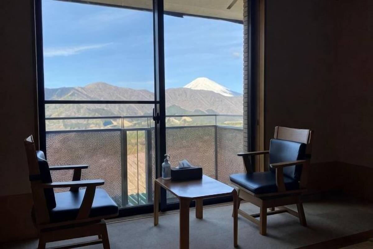 A balcony with a view of a mountain, two chairs, and a small table.