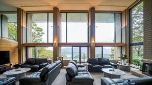 Un salón amplio con sofás de cuero, un televisor de pantalla plana y grandes ventanales con vistas a la montaña.