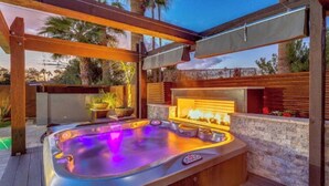 Un bain à remous avec un mur en pierre en arrière-plan et une pergola en bois au-dessus.