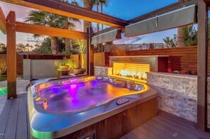 Relax in the hot tub surrounded by a serene atmosphere and lush greenery.