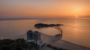 Un hôtel en bord de mer doté d’une architecture moderne, avec une longue jetée s’avançant dans la mer et offrant une vue sur le coucher de soleil sur l’océan.
