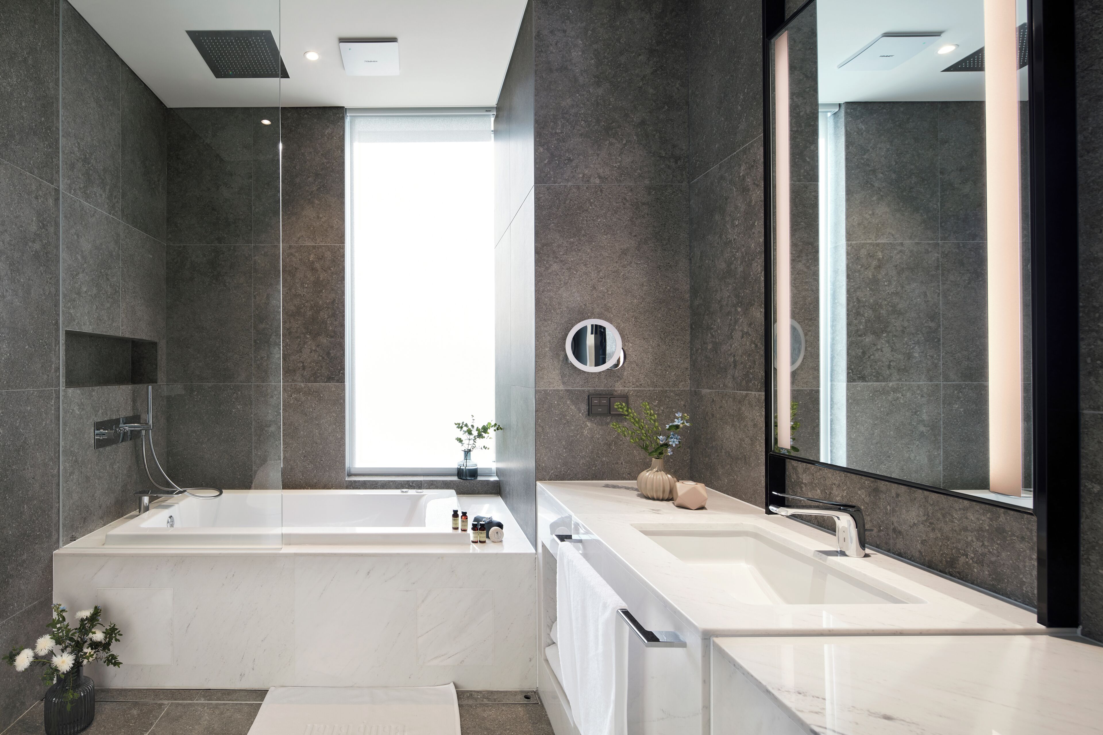 A modern bathroom with a large bathtub, a separate shower area, and a vanity with a mirror.
