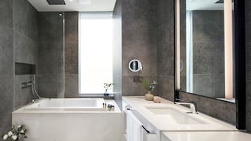 A modern bathroom with a large bathtub, a separate shower area, and a vanity with a mirror.