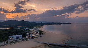 A coastal hotel with multiple floors, a beach view, and a bridge in the foreground.