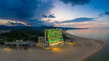 Un hotel de varios pisos con vista a la playa, situado cerca del agua.
