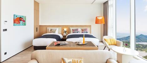 Une chambre d’hôtel moderne avec deux lits, un canapé, une petite table et une vue sur l’extérieur.