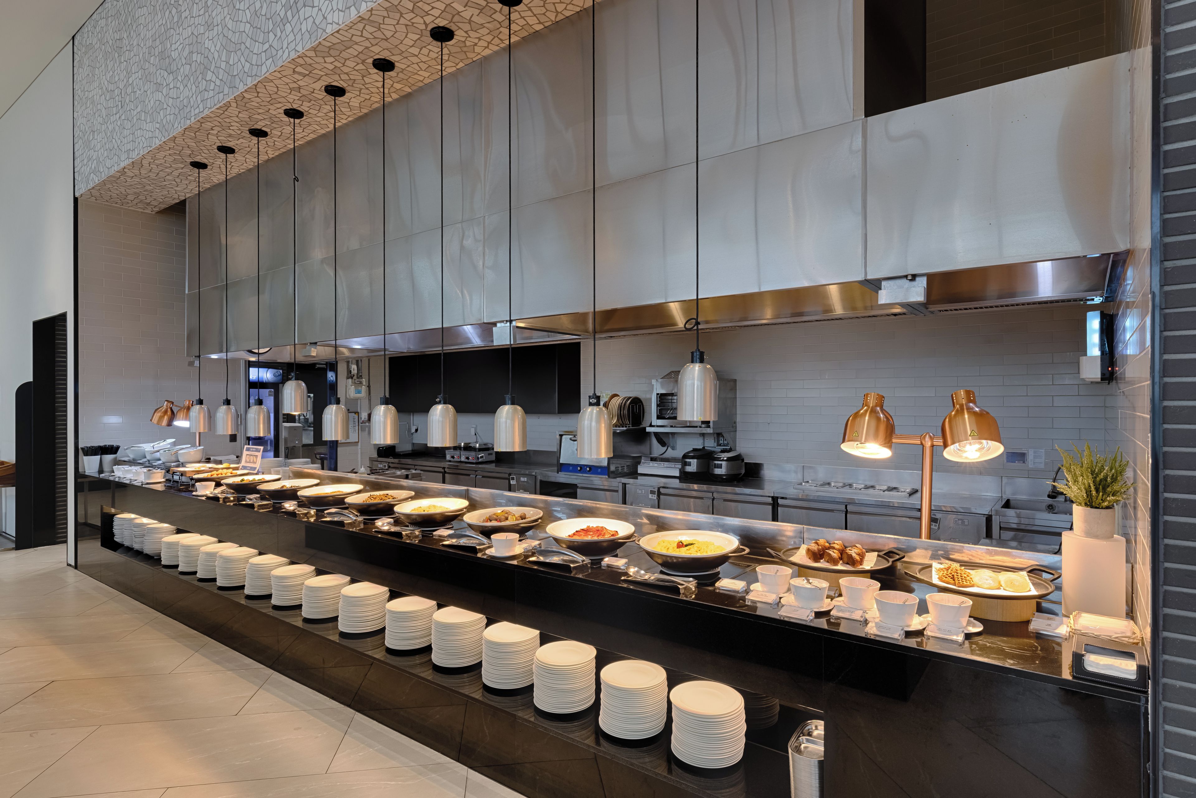 Un buffet avec plusieurs points de service, une grande variété de plats et une cuisine moderne en arrière-plan.