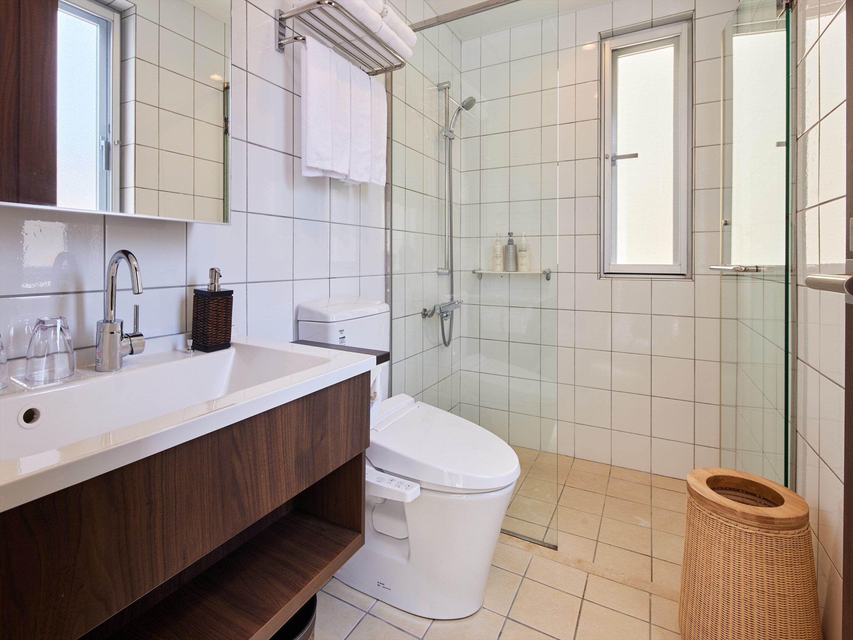 A modern bathroom with a white sink, a toilet, and a glass shower enclosure.