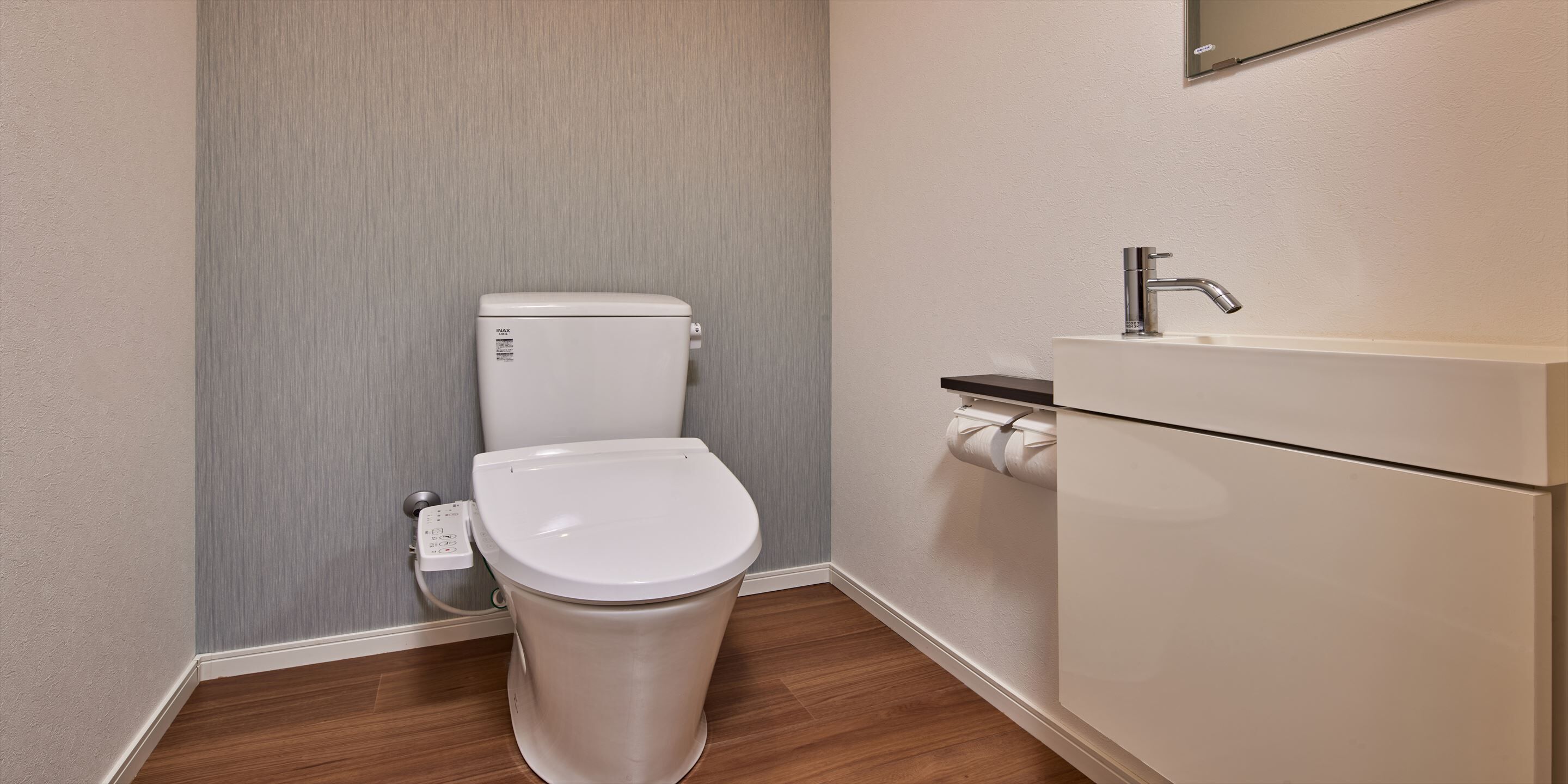 Un baño pequeño con inodoro, lavamanos y soporte para papel higiénico.