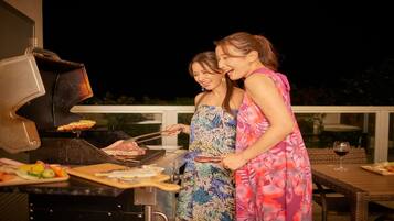 Two people grilling outdoors at night.