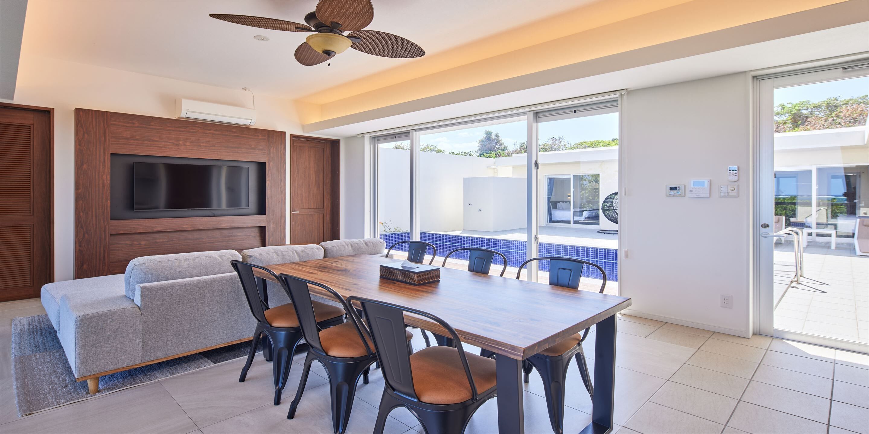 A modern dining area with a wooden table, grey sofa, and black chairs.