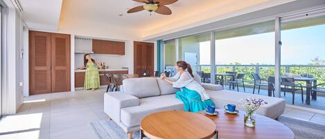 A modern living room with a sofa, a dining table, and a balcony with outdoor furniture.