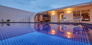 Ein moderner Poolbereich mit einem hellblauen Fliesenboden, einem Hängesessel und einer Liege.