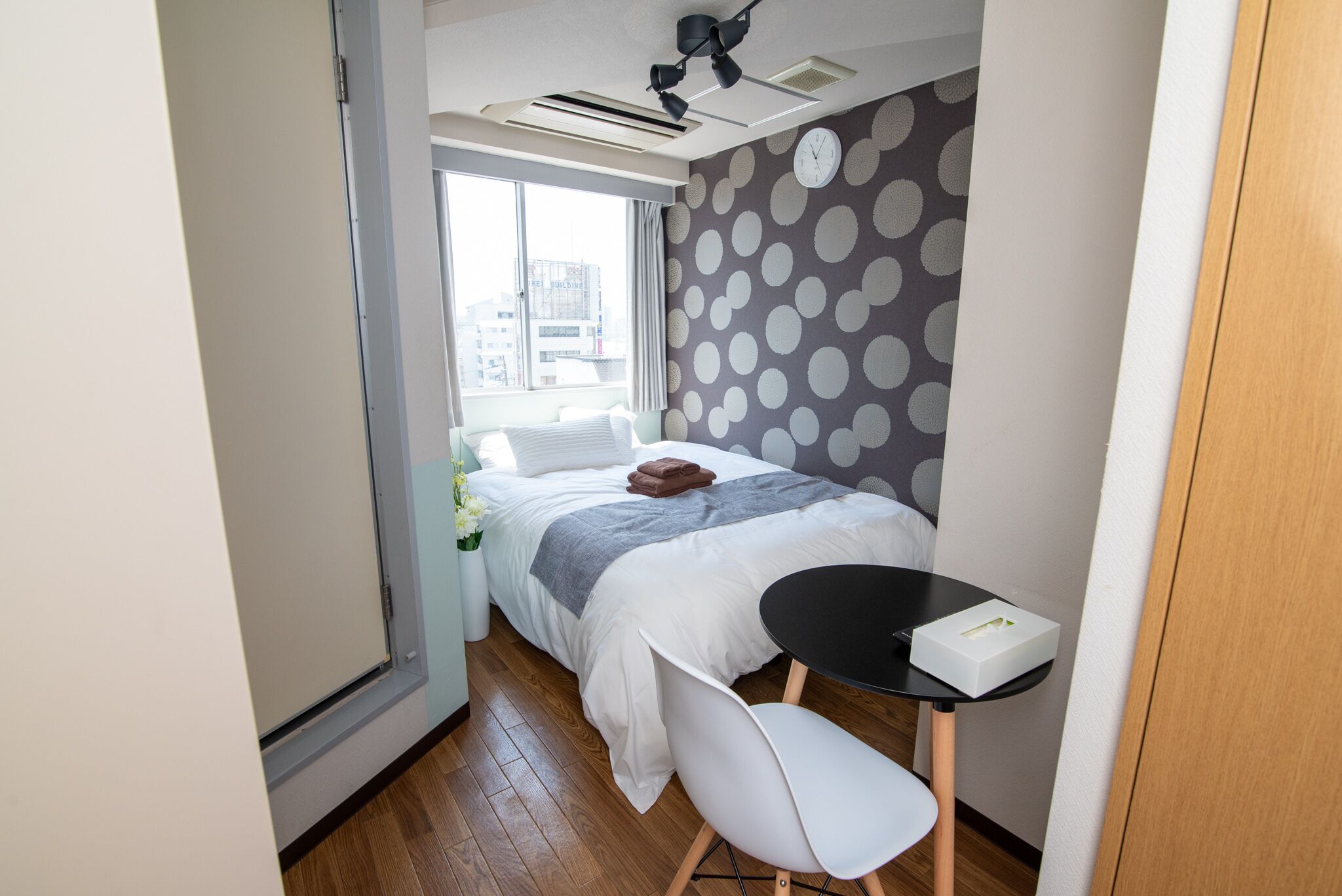 A compact hotel room with a bed, a small table, and a chair.