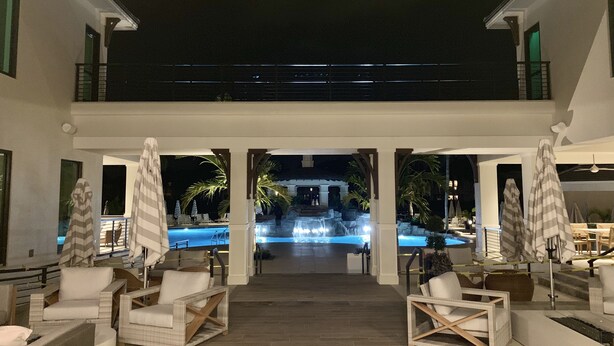 A pool area with lounge chairs and umbrellas, a water feature, and a view of a building in the background. - The Dunes! Walk to the beach! Unwind in this amazing Naples retreat! (Naples)
