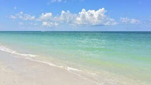 A beach with clear turquoise water and a sandy shore under a blue sky with scattered clouds. - The Dunes! Walk to the beach! Unwind in this amazing Naples retreat! (Naples)
