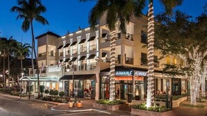 A multi-story hotel with balconies, palm trees, and storefronts. - The Dunes! Walk to the beach! Unwind in this amazing Naples retreat! (Naples)