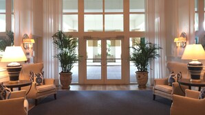 A lobby with a large entrance, two potted plants, a chandelier, and two lamps on either side. - The Dunes! Walk to the beach! Unwind in this amazing Naples retreat! (Naples)