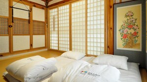 Una habitación japonesa tradicional con suelo de tatami, puertas correderas shoji y una cama con ropa blanca.