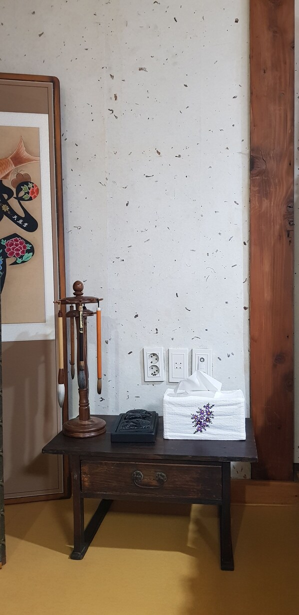 A wooden table with a decorative stand, a tissue box, and a small black object on it. - Gallery Jin Hanok Guesthouse (Gyeongju)