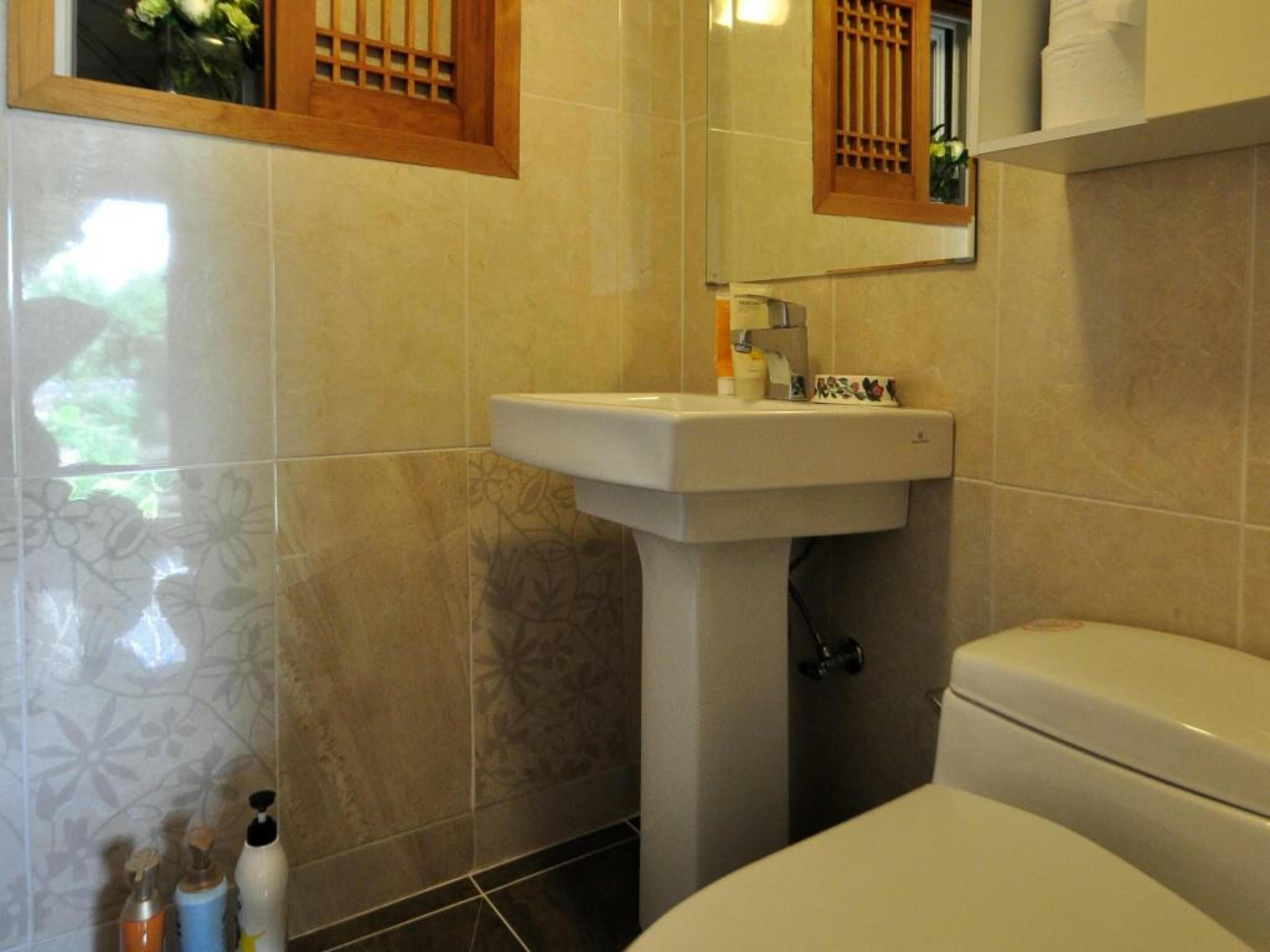A bathroom with a toilet, sink, and mirror.