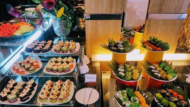 Un bufé con diversos platos y postres, incluyendo pasteles y fruta.