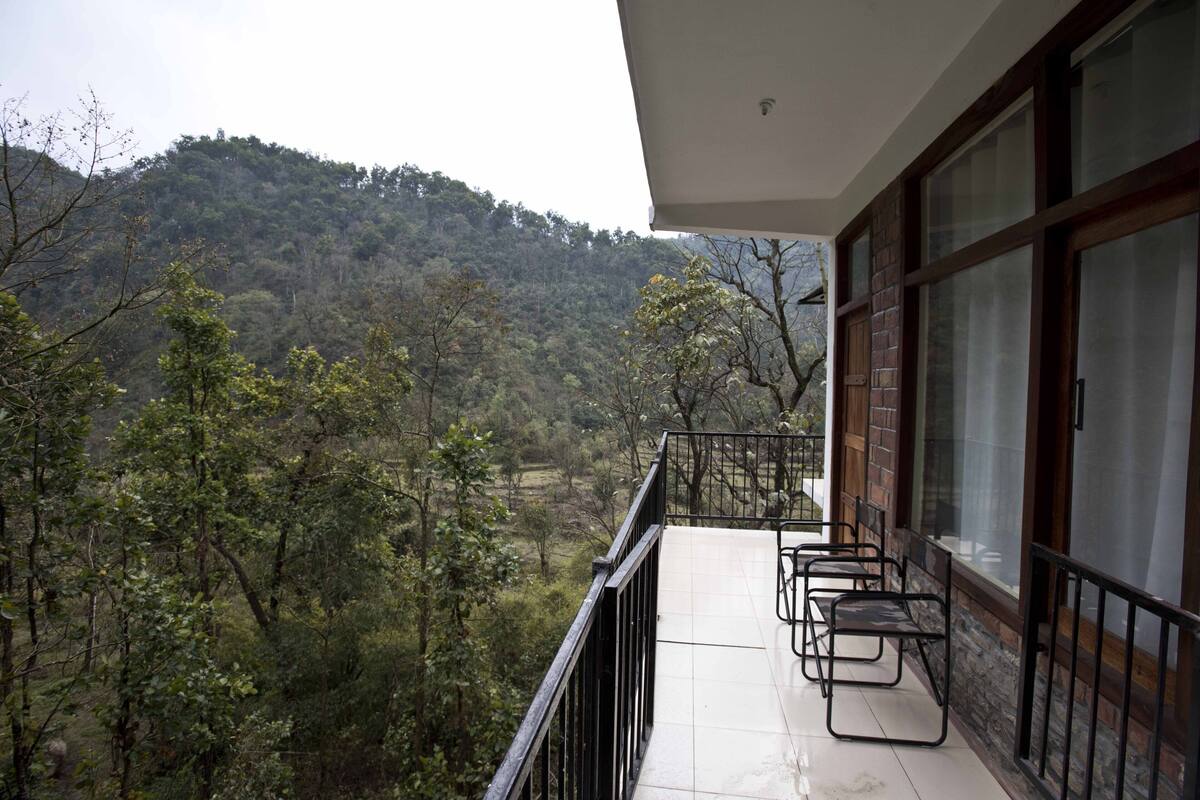 A balcony with a view of a forested hillside.