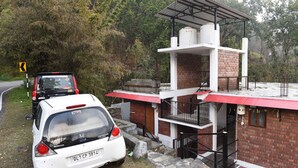 A white Honda car parked next to a building with a red roof and a balcony. - Corbett Riviera (Lansdowne)