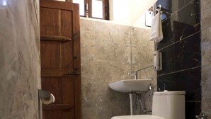 A bathroom with a wooden door, a white toilet, a sink, and a mirror. - Corbett Riviera (Lansdowne)