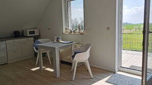 Une cuisine moderne avec un coin repas, une grande fenêtre et une vue sur un paysage verdoyant.