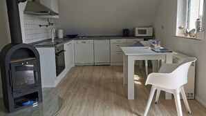 Une cuisine moderne avec des meubles blancs, un four noir, un four à micro-ondes et un coin repas comprenant une table et des chaises blanches.