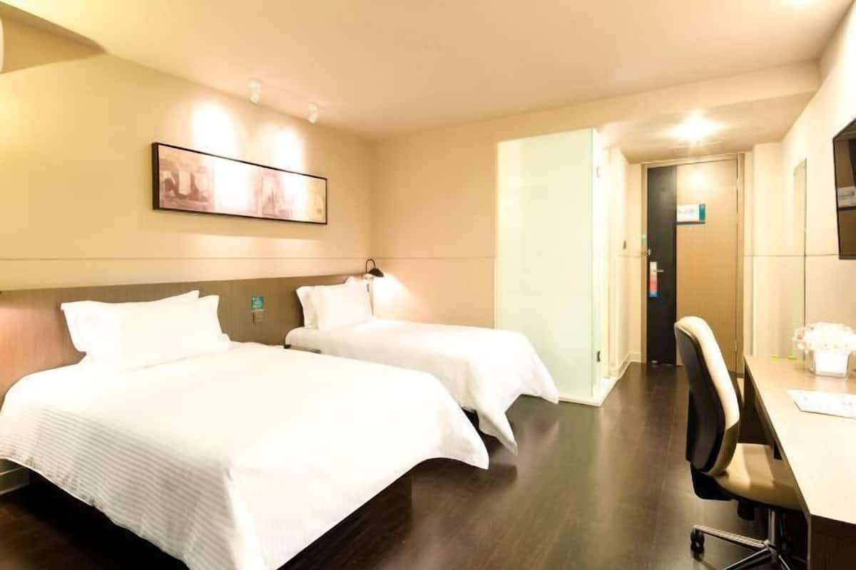 A hotel room with two beds, a desk, and a chair.